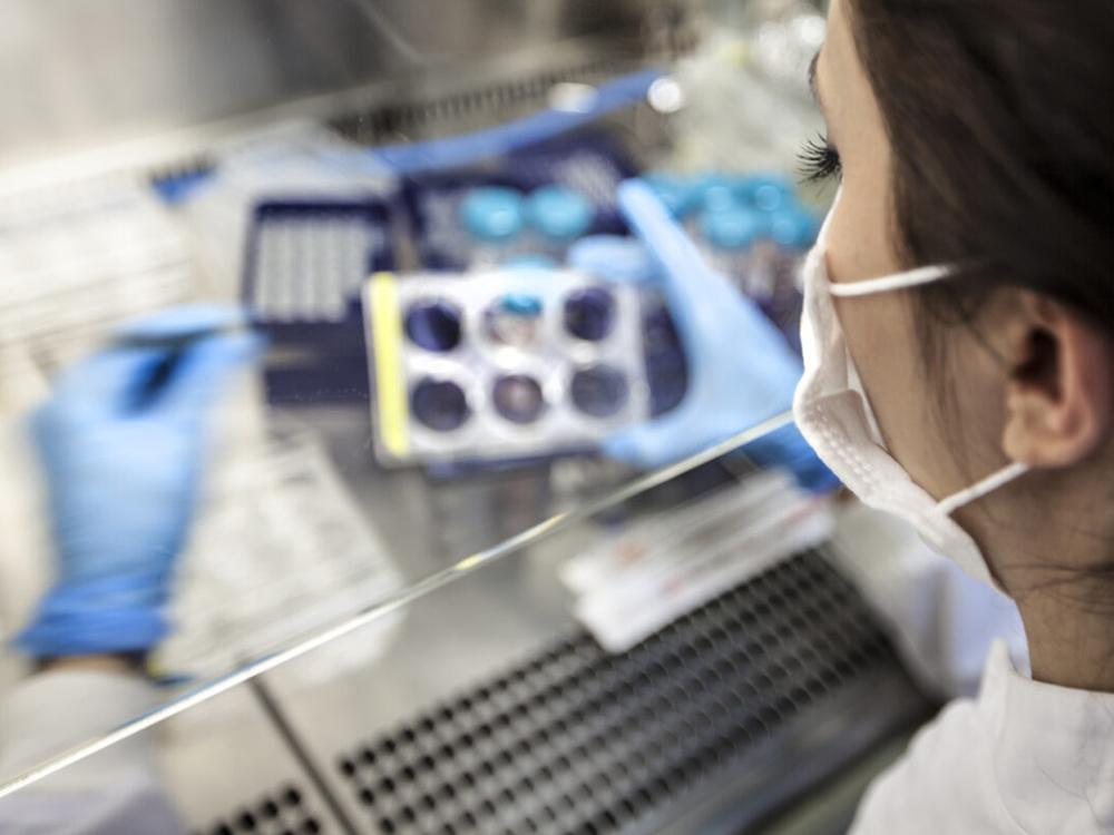 A scientist in a white coat works in a lab